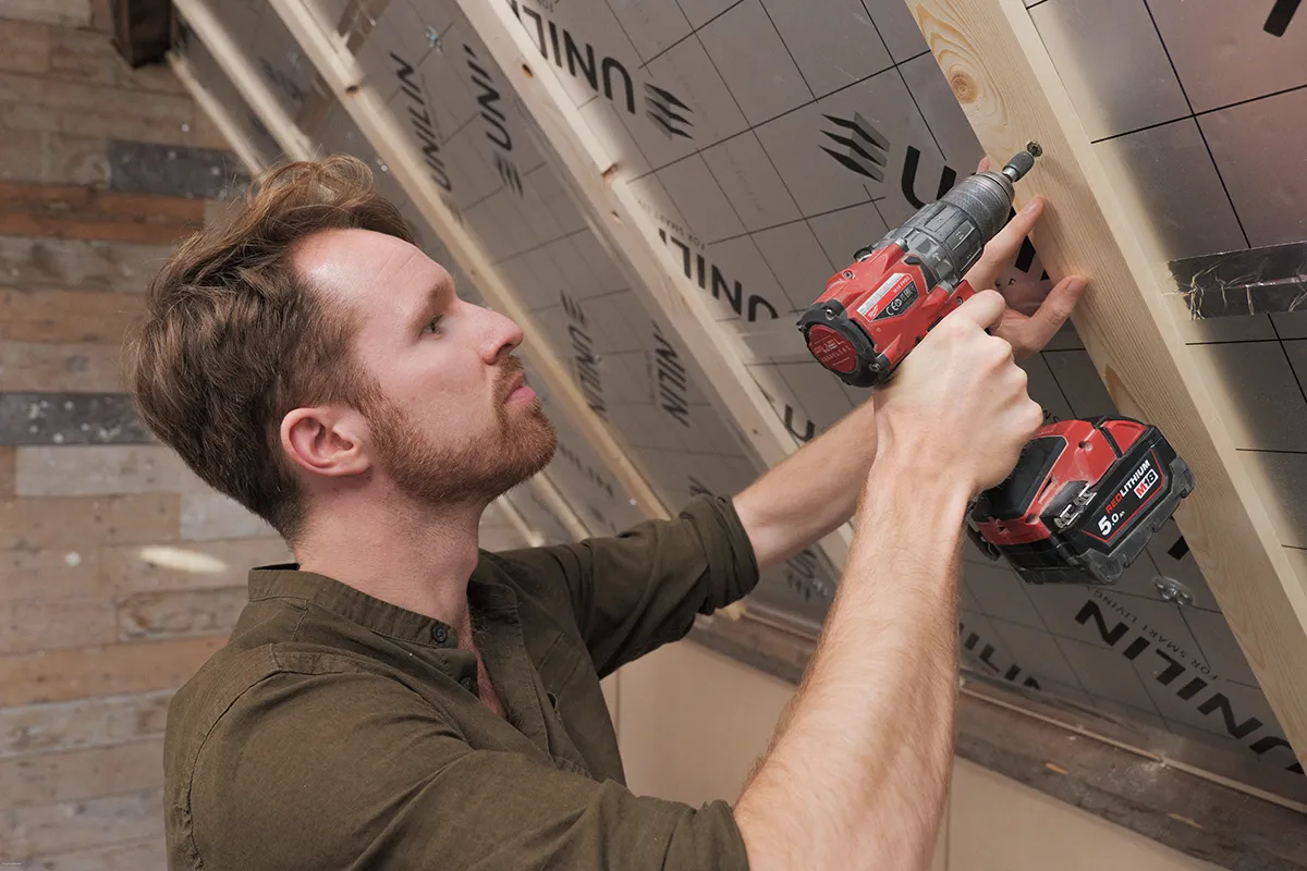 Bewoner is zijn schuine dak op zolder aan het isoleren